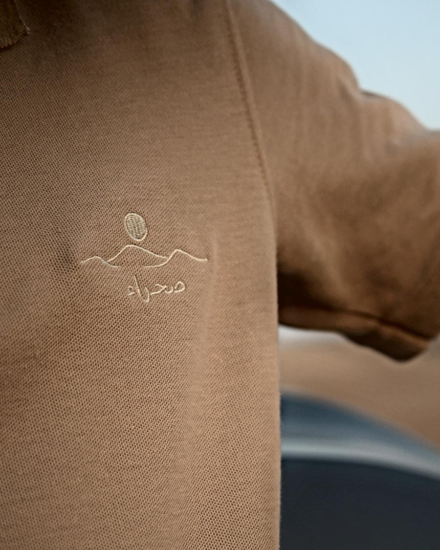 The Sahra Polo, shoulder and chest — the embroidered mark beside the shoulder seam
