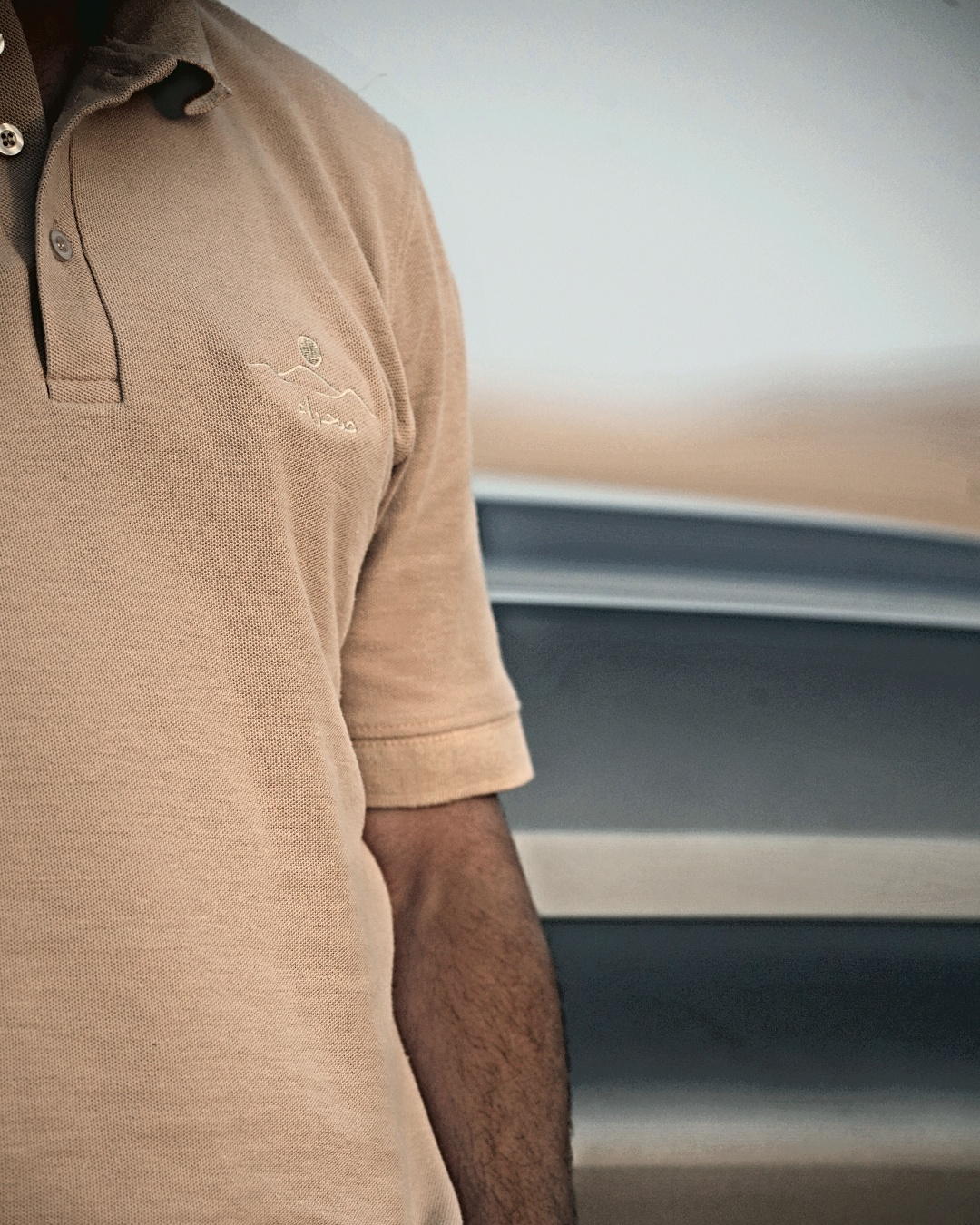 The Sahra Polo, chest and sleeve — the embroidered mark and the sleeve cuff