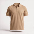 The Sahra Polo in sand, front — 240gsm cotton piqué with a three-button placket and the embroidered صحراء mark on the chest