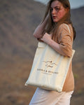 The Sahra Tote in natural canvas, carried over the shoulder in the Hajar mountains